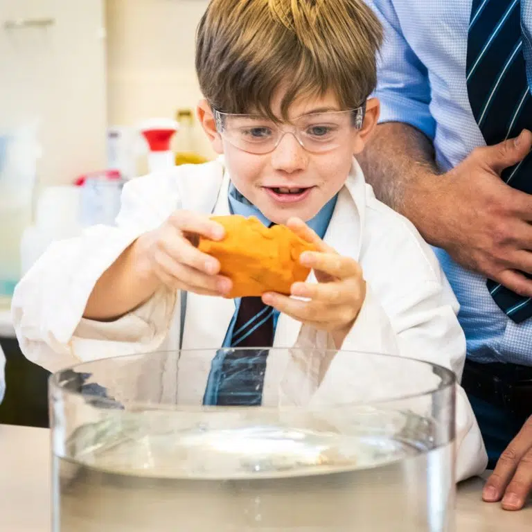 Boy holding a piece of clay into water