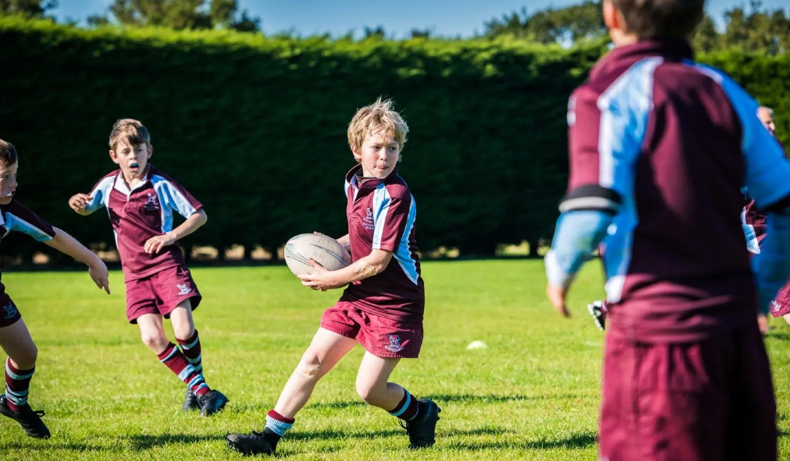 Group of male students playing rugby in the purple Holmwood kit