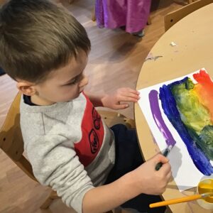 boy painting onto a piece of paper