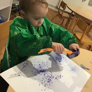 boy spraying paint onto large piece of paper