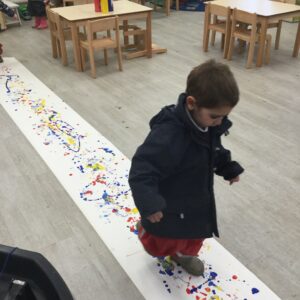 student walking over a strip of paper with paint